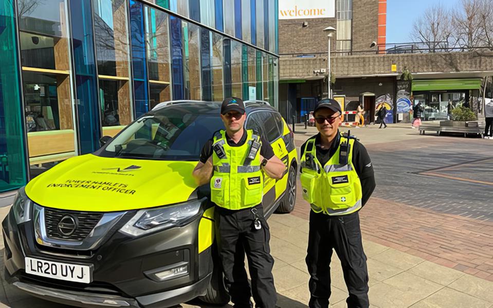 2 Tower Hamlets Enforcement Officers with their patrol car in front of Chrisp Street Idea Store