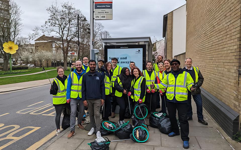 Photo of a group of rubbish collecting volunteers in high viz vests, in front of a bus stop