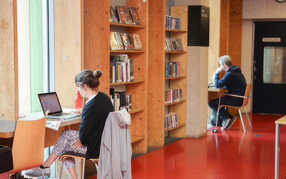 People working on their laptops in a bright, spacious library space