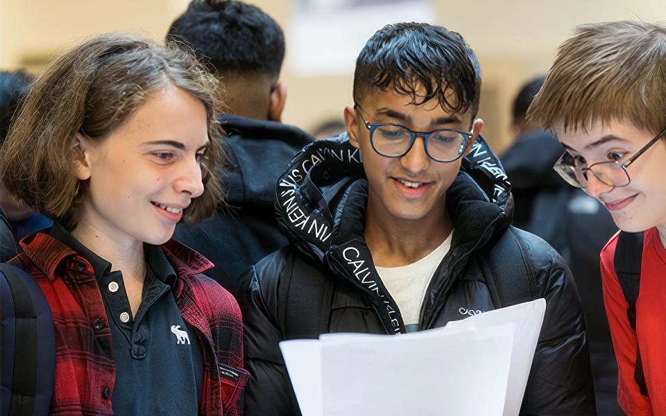 Three youngsters examine some paperwork. Are these exam results?